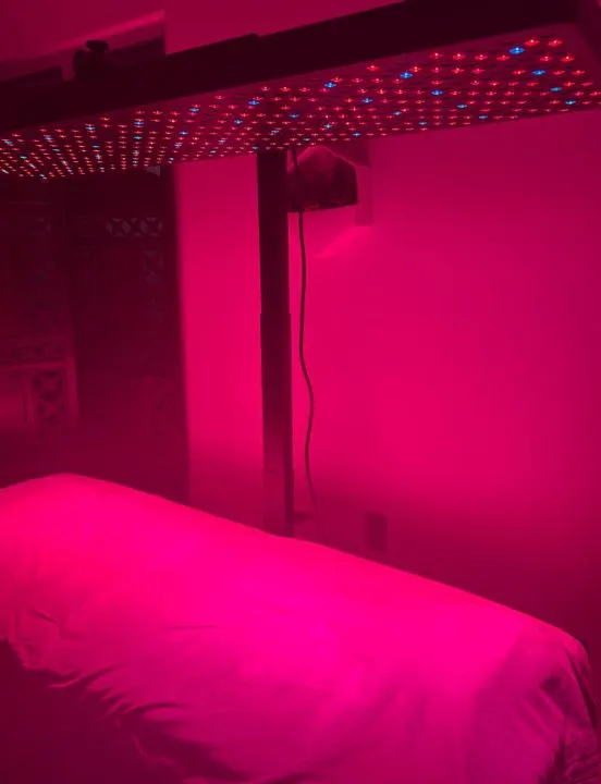 The Big Red full-body light bed glowing red in a private room at AND Wellness